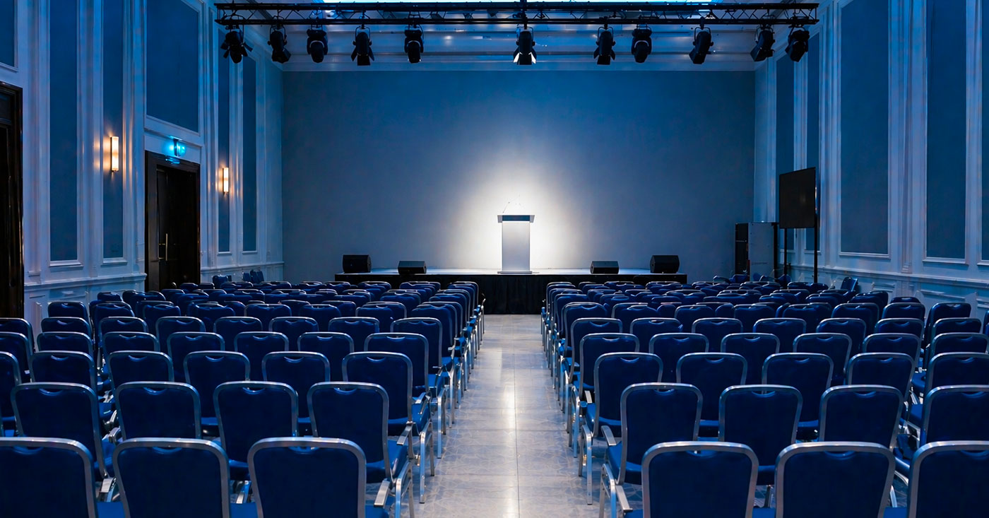 Sala di un congresso buia con sedie vuote e spotlight sul palco